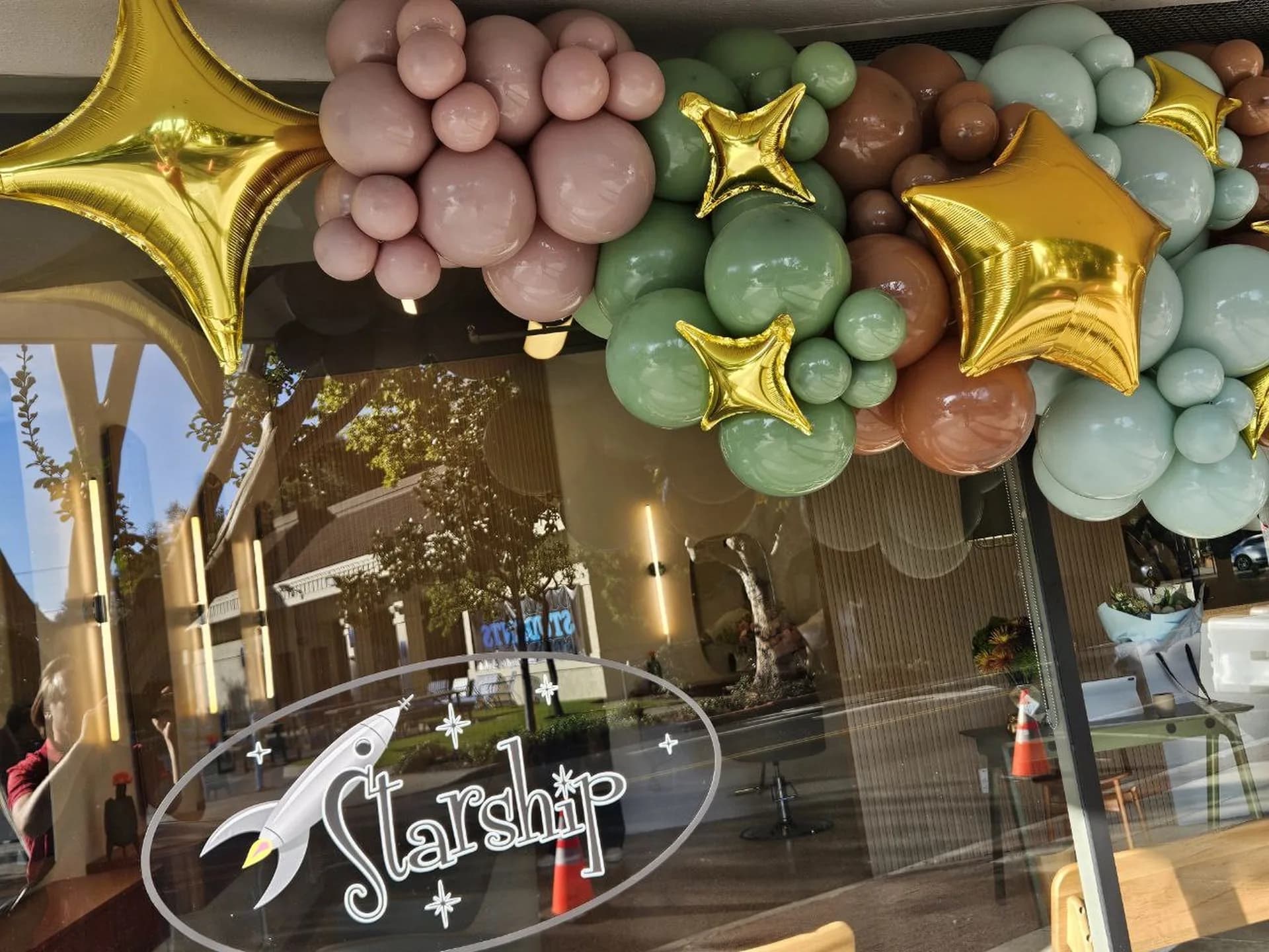 Salon Grand Opening in San Carlos, California: storefront balloon garland with gold star accents, view 2 of 5.