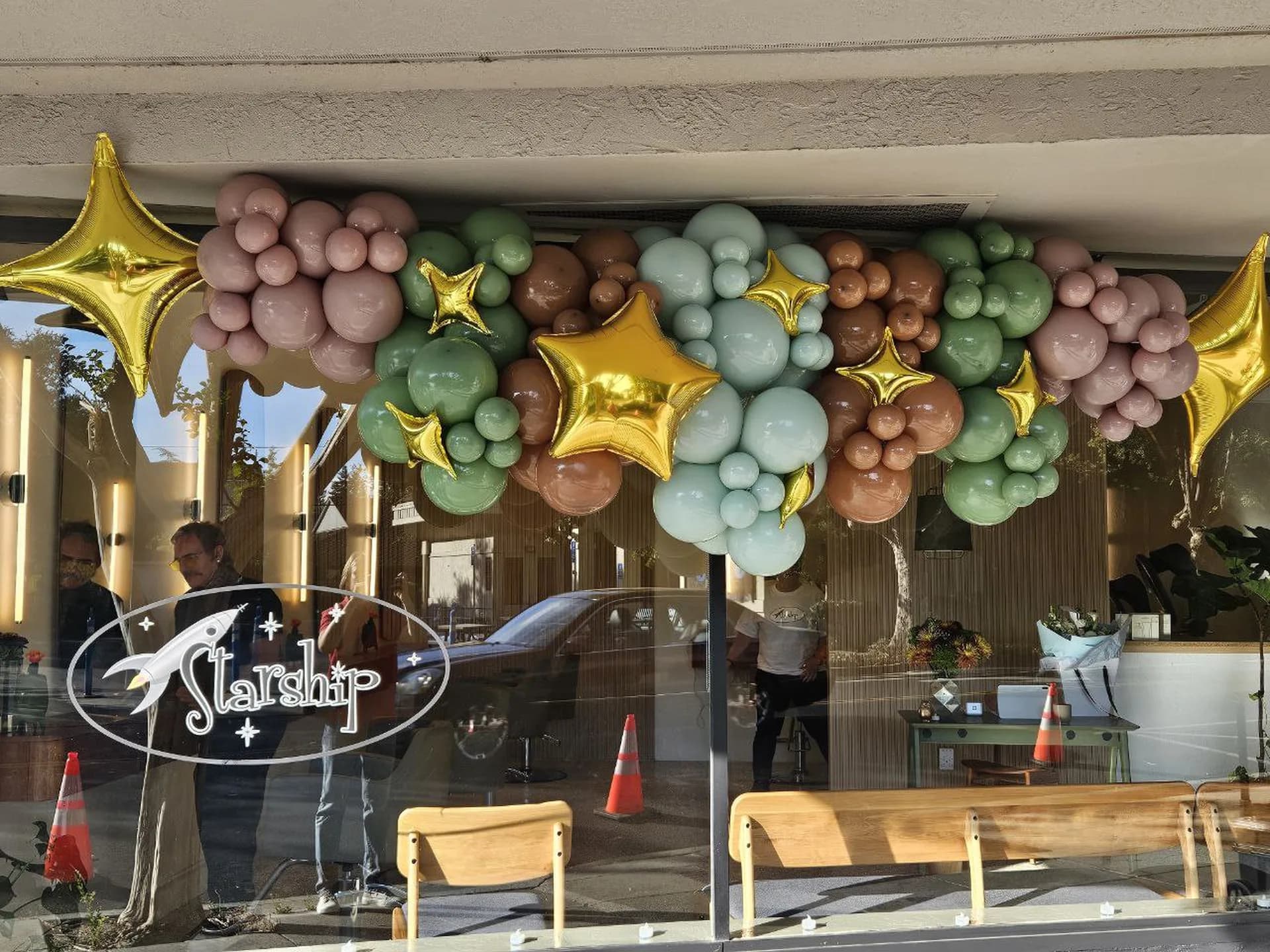 Storefront balloon garland with gold star accents installed on site for the Salon Grand Opening in San Carlos, California, frame 5 of 5.