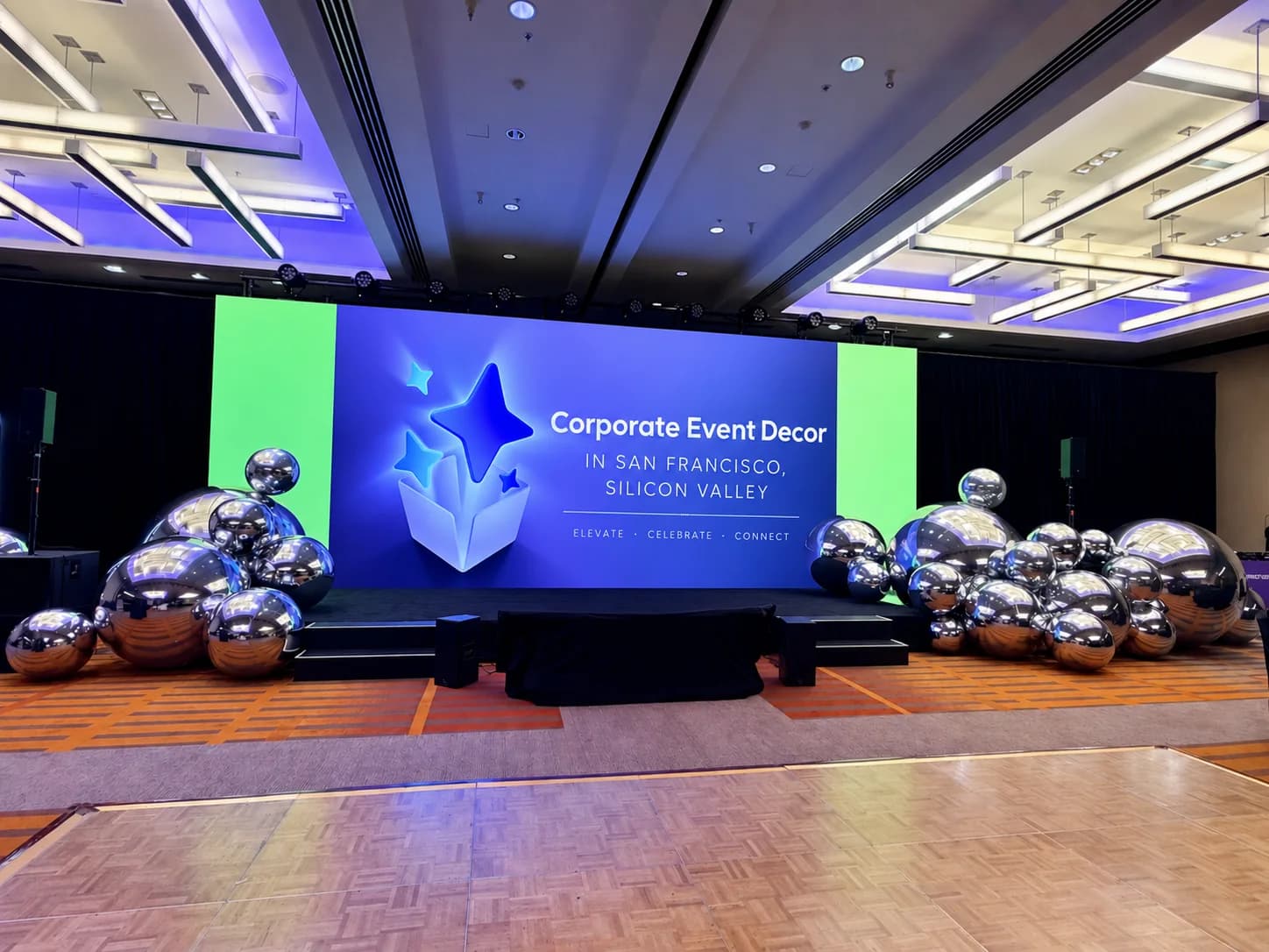 Mirror-chrome balloon spheres framing a conference stage in a San Francisco Bay Area hotel ballroom