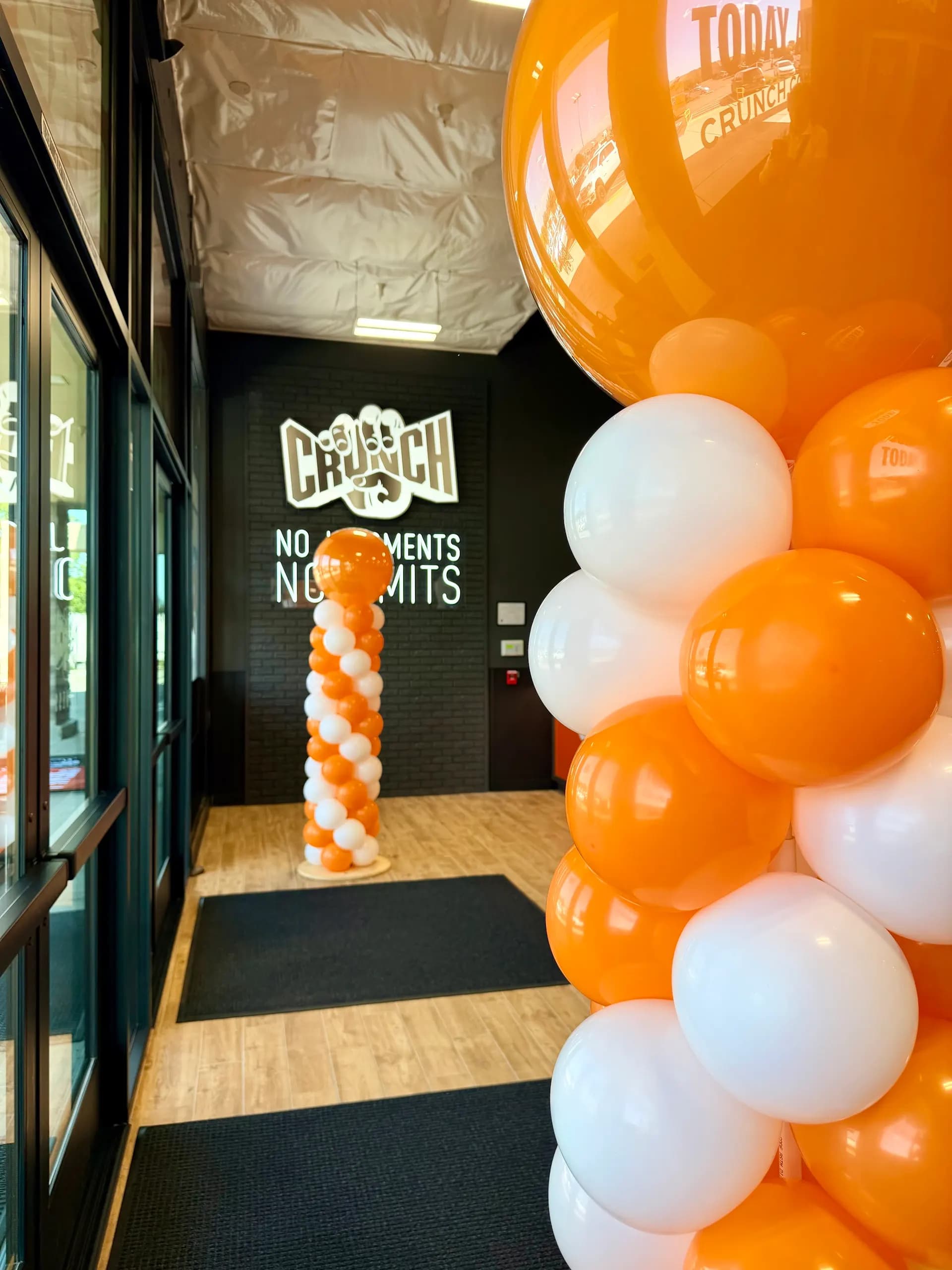 Orange and white balloon arch and entrance columns at the Crunch Fitness gym grand opening in Gilroy, California.