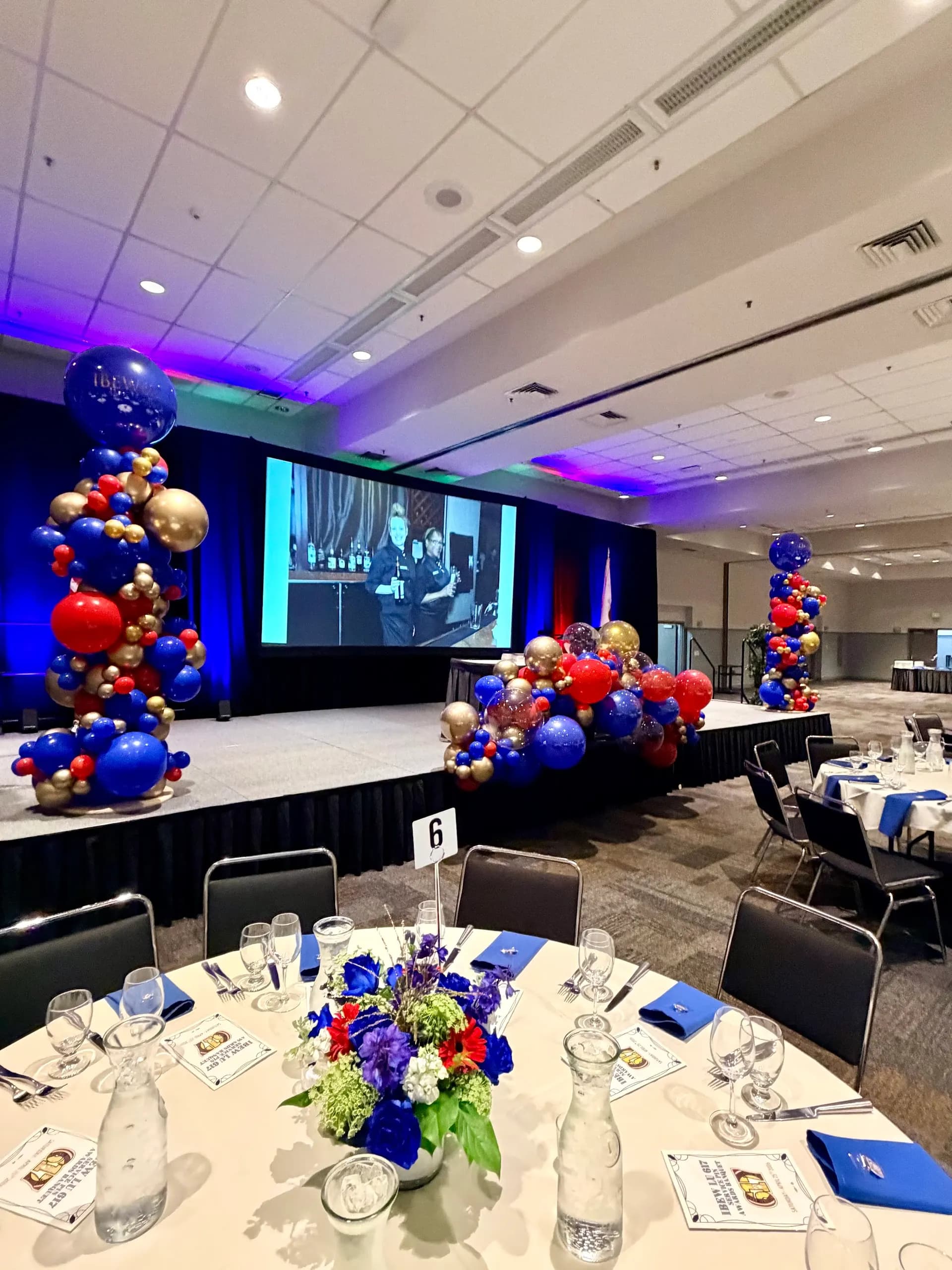 Branded balloon backdrop and stage columns in red, royal blue and gold, Corporate Gala & Conference, San Mateo, California — view 7 of 8.