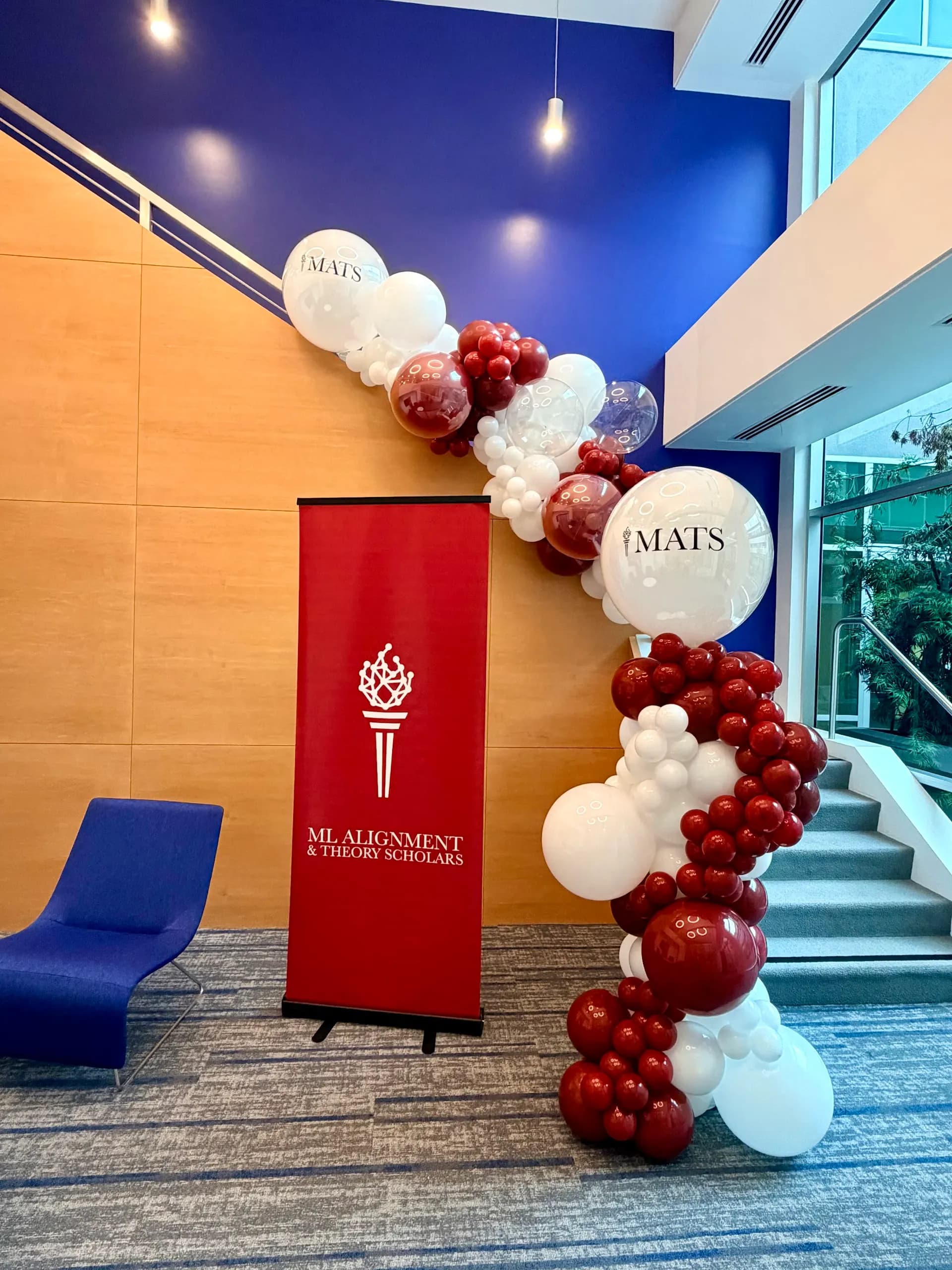 Organic balloon garland around a branded event banner for MATS at the ML Alignment & Theory Scholars Event in San Francisco Bay Area.